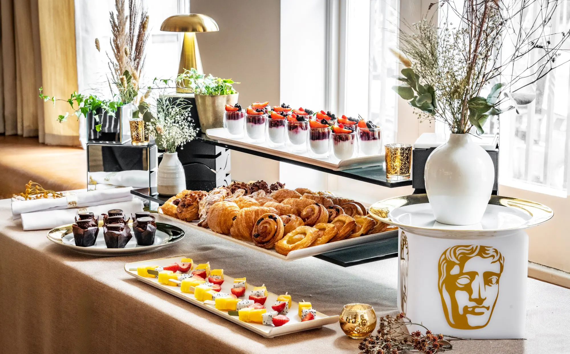 A three tier selection of fruits and pastries.
