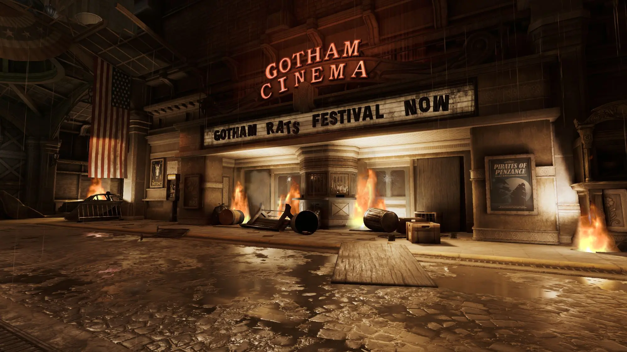 A rundown building with a sign that says Gotham Cinema and has burning trashcans outside it's doors. It also has an old cinema sign that reads 'Gotham Rats festival now'.