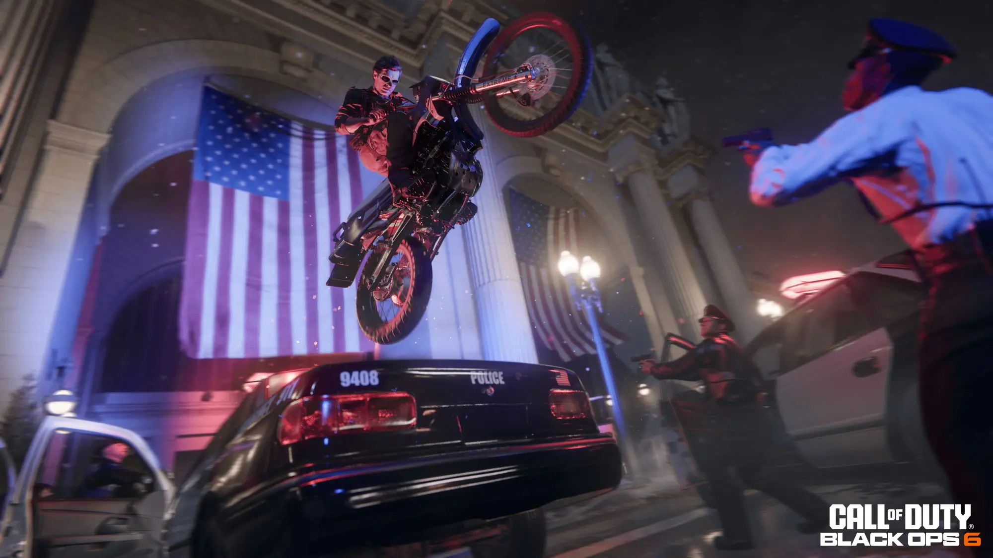 An animated image of a man on a motorcycle jumping over a police car in front of a building with a giant US flag on it.